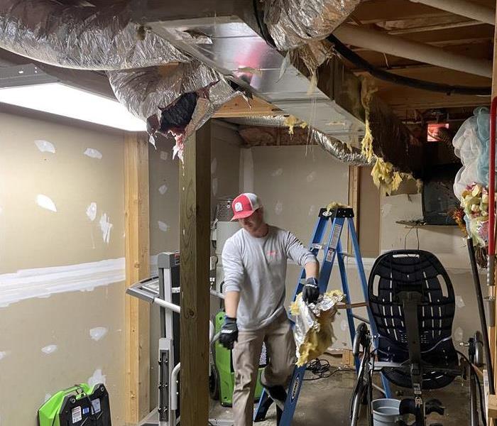 man with hat working with wet insulation above